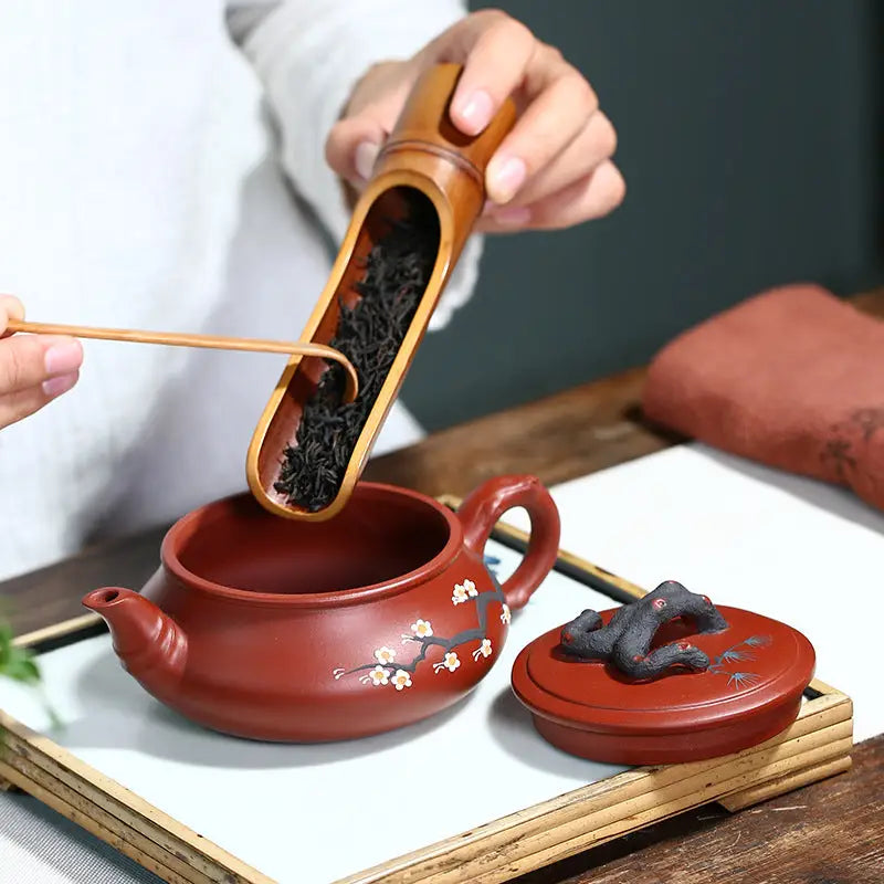 Red-brown handcrafted Yixing Zisha teapot with Plum Blossom motif for Gongfu tea brewing