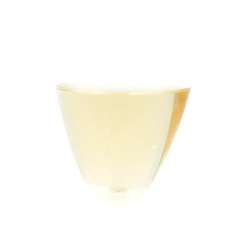 Glass of white wine with orchid fragrance tea from Ice Island region featuring xiaoxiangshui raw pu-erh