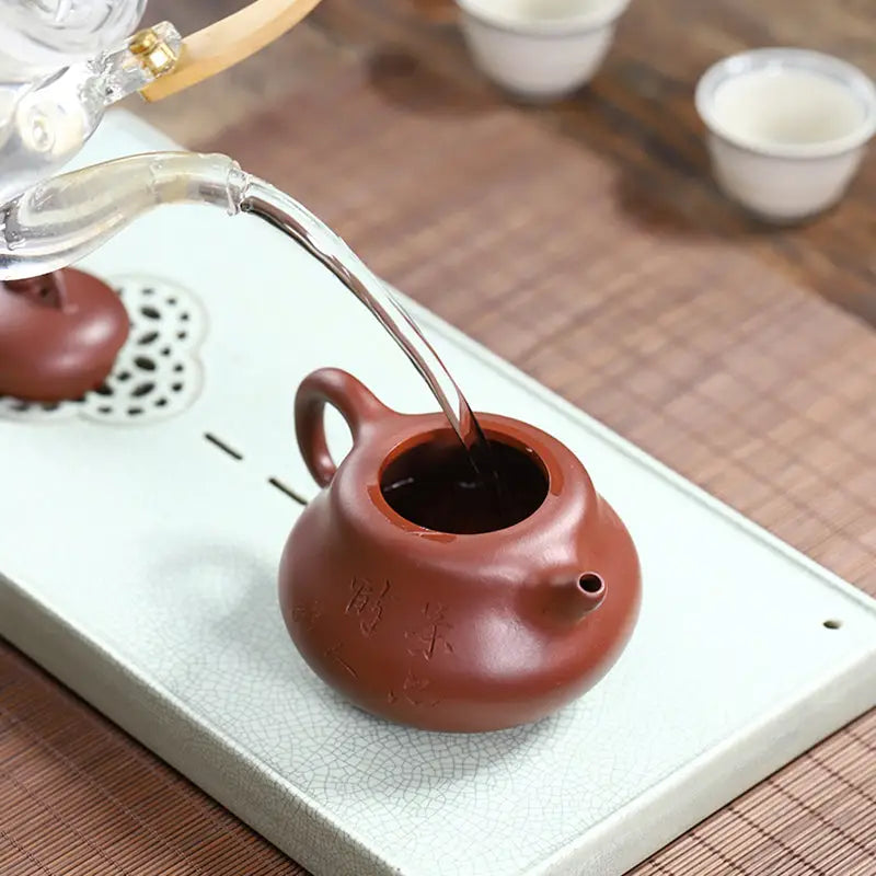 Brown ceramic yixing zisha teapot being filled from Scholar’s Rest handcrafted Yixing art
