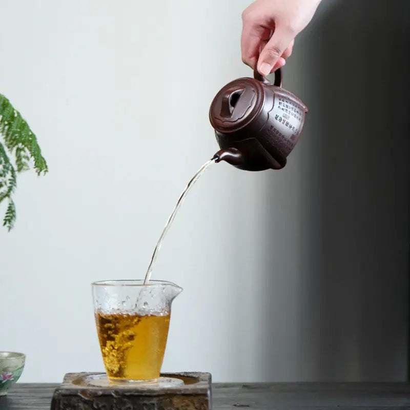 Brown ceramic teapot pouring tea from Scripture Serenity Yixing Zisha collection