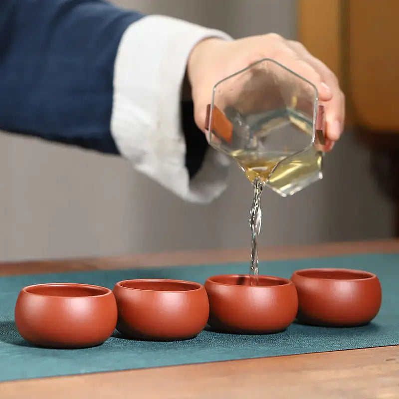Tea being poured into small silent curve cup made of Yixing Zisha clay for gongfu tea