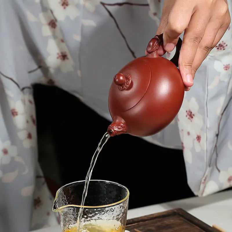Reddish-brown Yixing Zisha Teapot Silent Sentinel pouring authentic purple tea liquid
