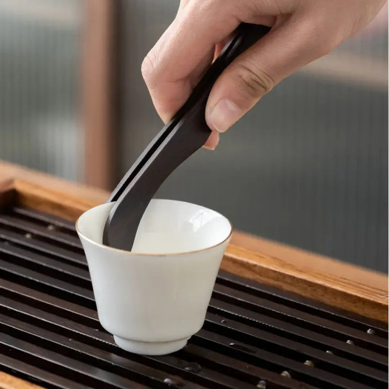 Black tea tongs in a white cup from the Six Gentlemen Tea Set for Gongfu Tea Ceremony