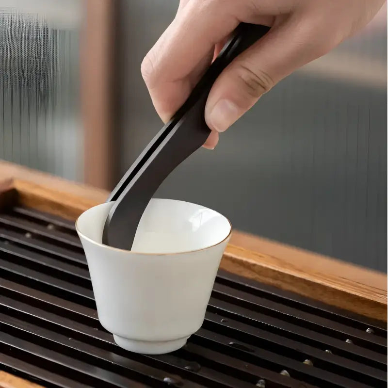 Black tea tongs in a white cup from the Six Gentlemen Tea Set for Gongfu Tea Ceremony