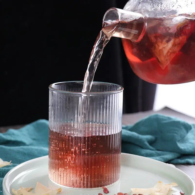 Ribbed glass being filled with red herbal tea to boost sleep quality and reduce hair loss