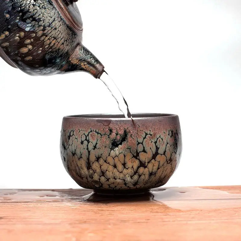Ornate Smoke Teapot with tenmoku glaze pouring gongfu tea in handcrafted Jianyang style
