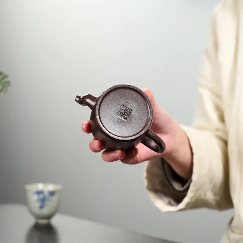 Brown ceramic teapot bottom featuring carved crane and pine motif in Soaring Tranquility Yixing Zisha Teapot