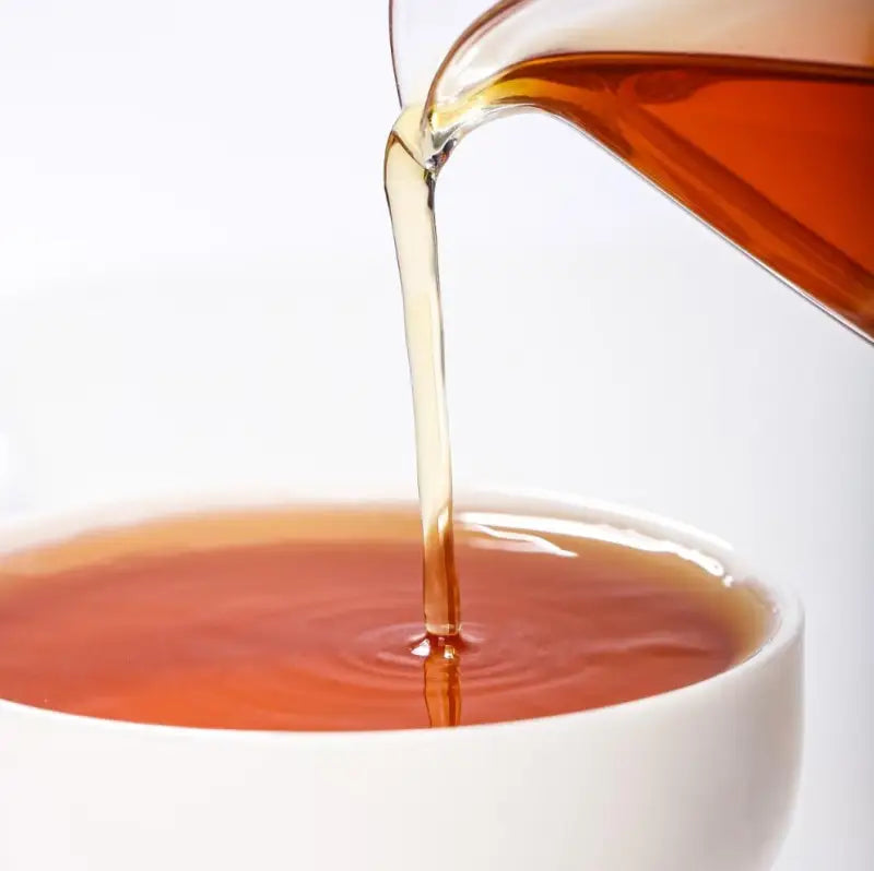 Pouring amber liquid from Spring Beauty Tanyang Gongfu Black Tea highlighting tea craftsmanship