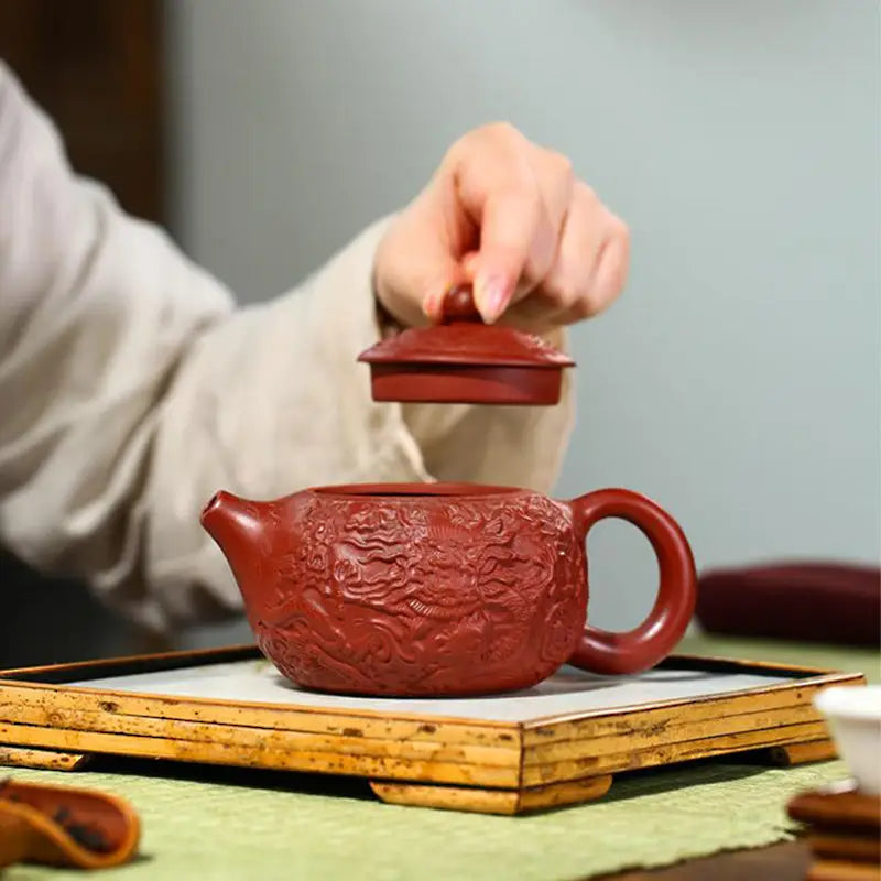Red-brown Yixing Zisha clay teapot with intricate dragon relief for imperial roar tea brewing