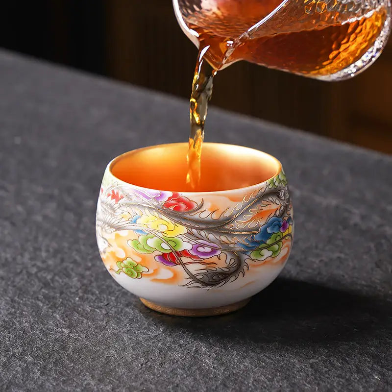 Porcelain tea cup decorated with a dragon being filled for gongfu tea brewing