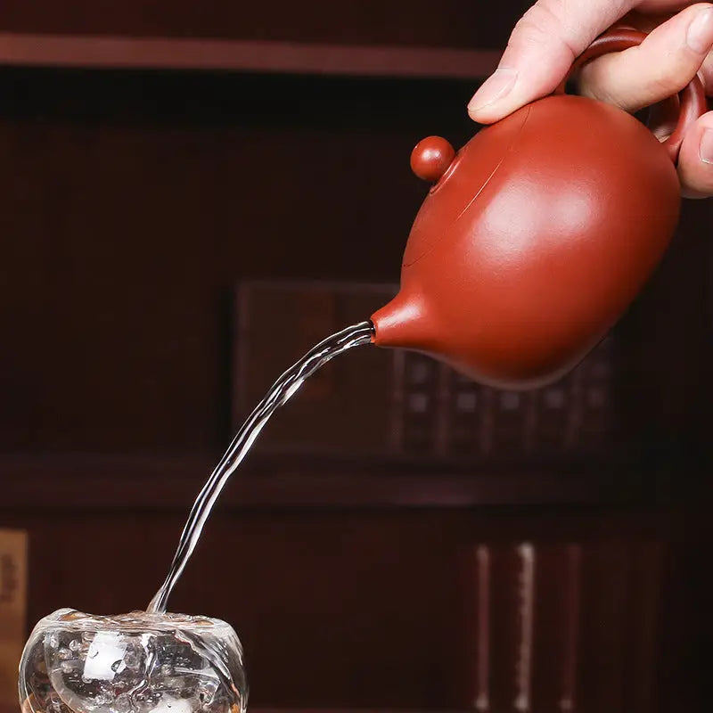 Reddish-brown teapot pouring water from The Still Moon handmade Yixing Zisha red clay