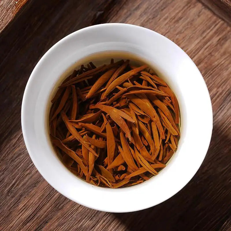 White bowl filled with golden tea leaves of Tongmu Jin Jun Mei 2025 black tea
