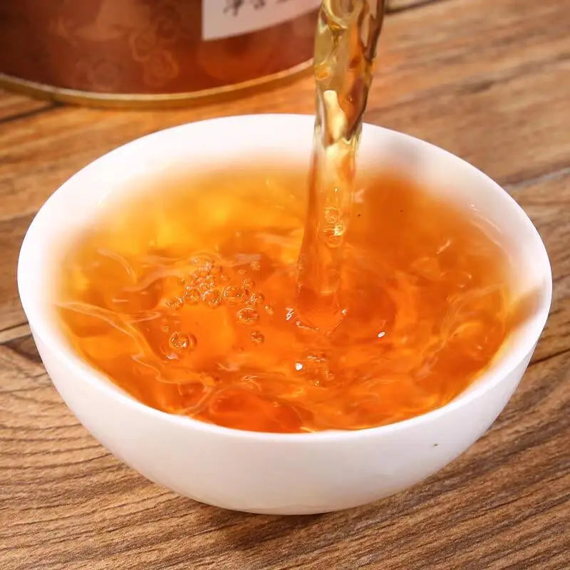 Amber black tea liquid pouring into a white bowl for Tongmu Jin Jun Mei 2025 Golden Eyebrow Black Tea