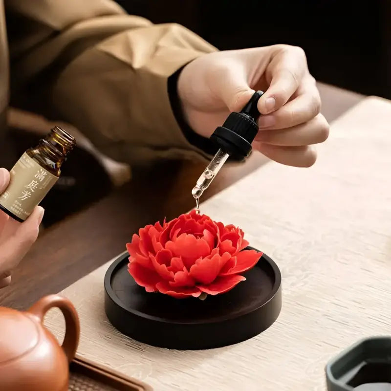 Aromatic oil dripped onto a red diffuser in the Tranquil Bloom Tea Set with Yixing Zisha Zisha Teapot