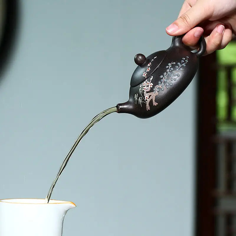 Dark Twilight Plum Yixing teapot pouring liquid, featuring hand-painted plum blossoms on black Zisha clay