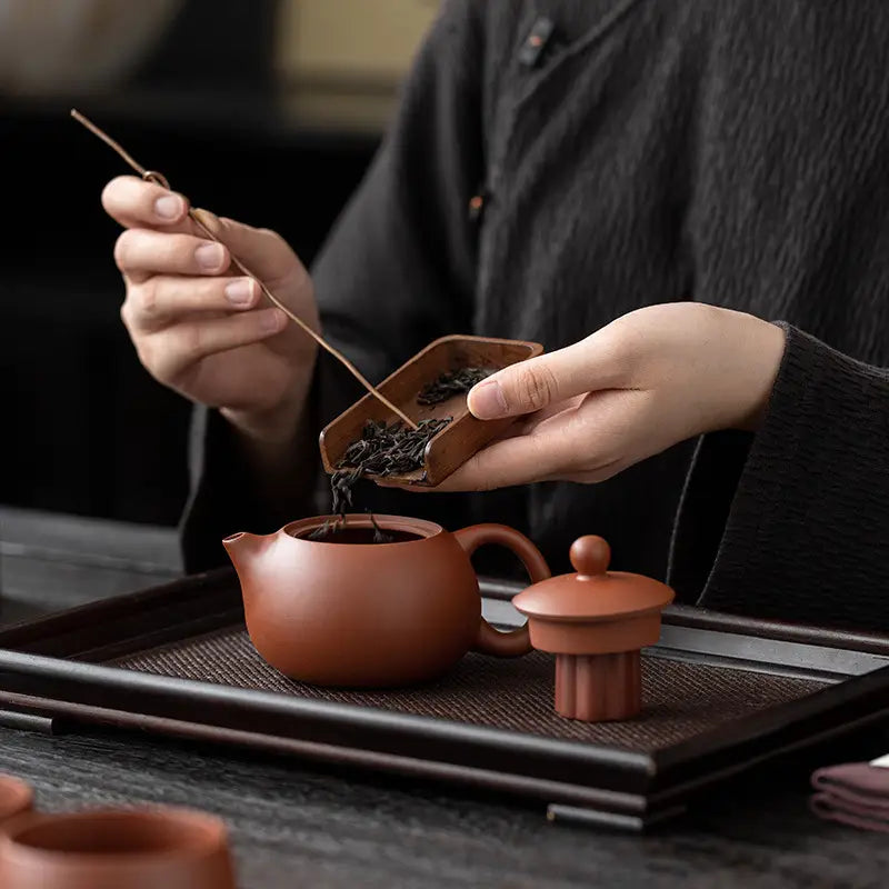 Earthenware Verdant Whisper Tea Set with Yixing Zisha green tea leaves being poured