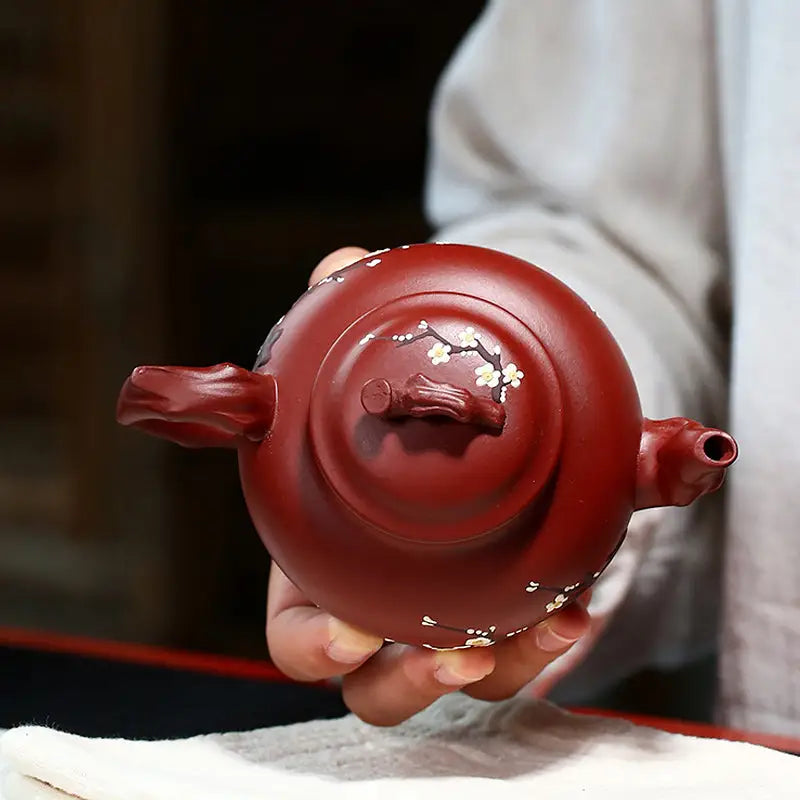 Reddish-brown Yixing teapot with hand-painted plum blossoms in authentic Zisha clay