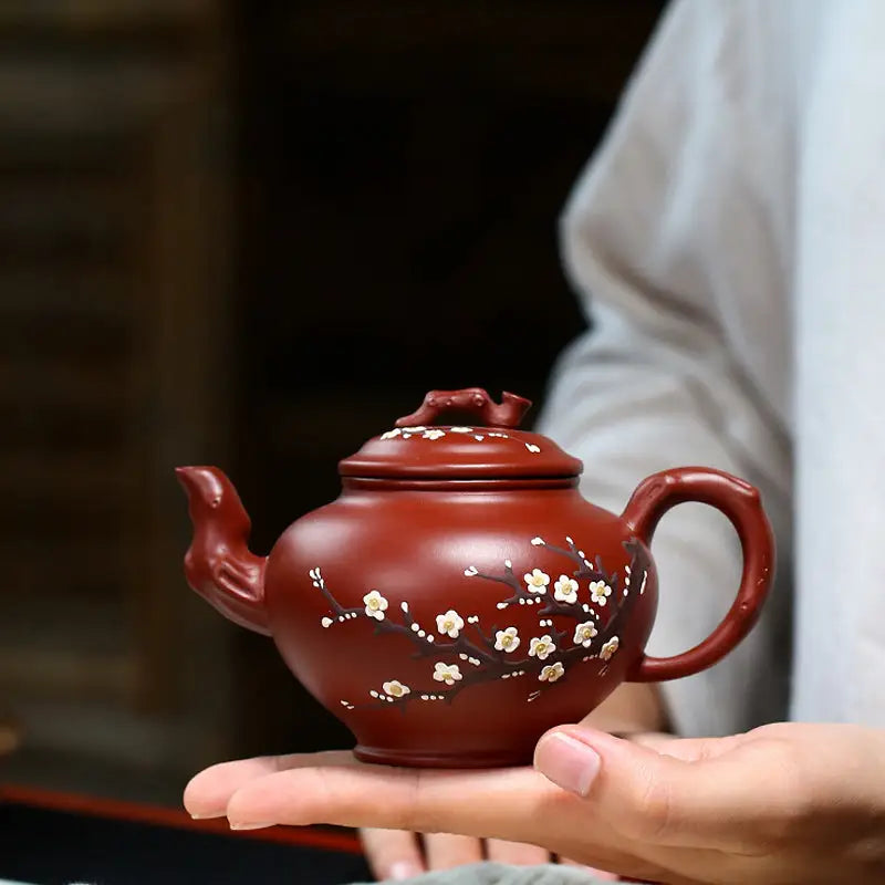Reddish-brown Yixing teapot with hand-painted plum blossoms in authentic Zisha clay