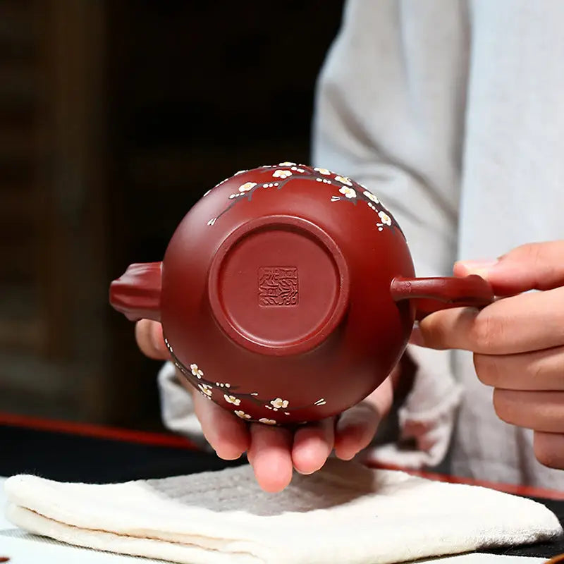 Reddish-brown Yixing teapot with hand-painted plum blossoms in authentic Zisha clay