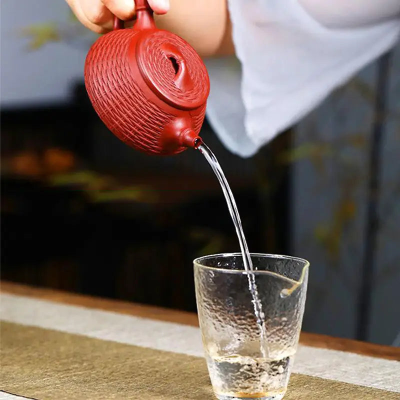 Textured Woven Whispers Yixing Teapot in Zisha Clay pouring water, showcasing craftsmanship