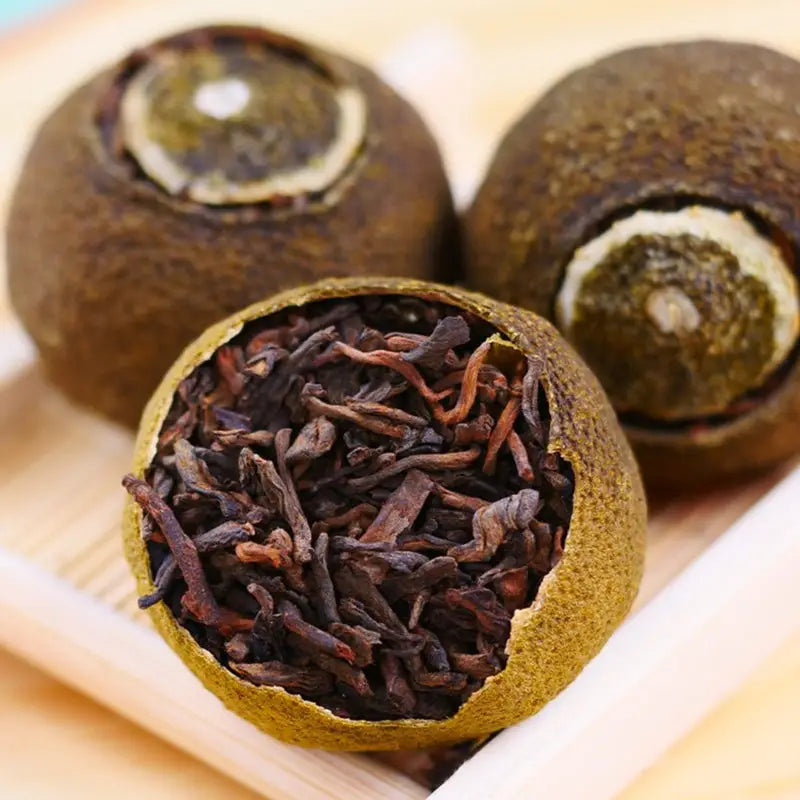 Tangerine tea balls in a teapot with Xiao Qing Gan Pu’er Tea Leaves and matching mugs