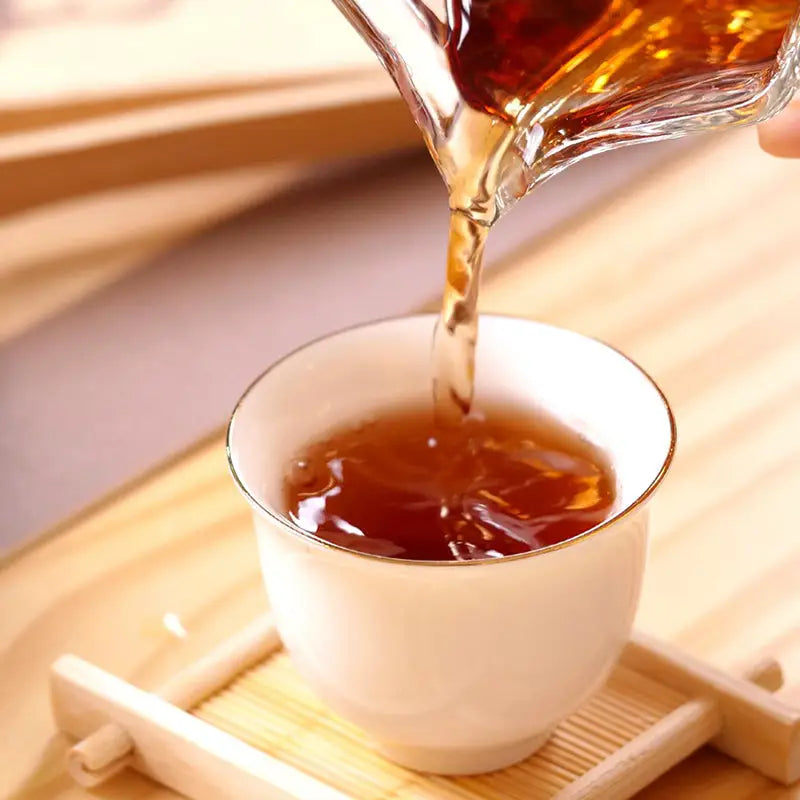 Tea being poured into a white mug from a teapot with Xiao Qing Gan Pu’er Tea Leaves